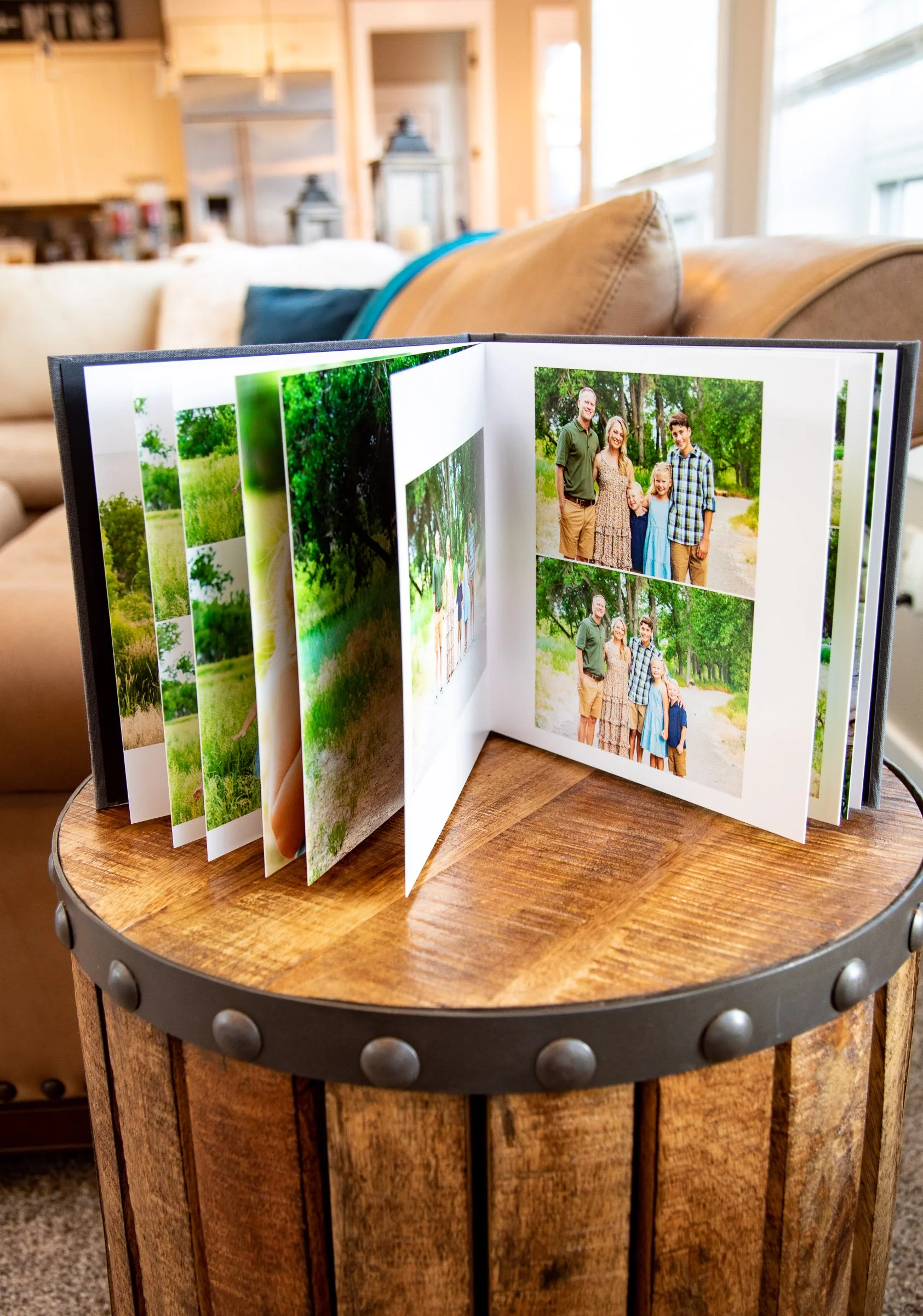 Open photo album with family pictures on a wooden side table in a cozy living room.