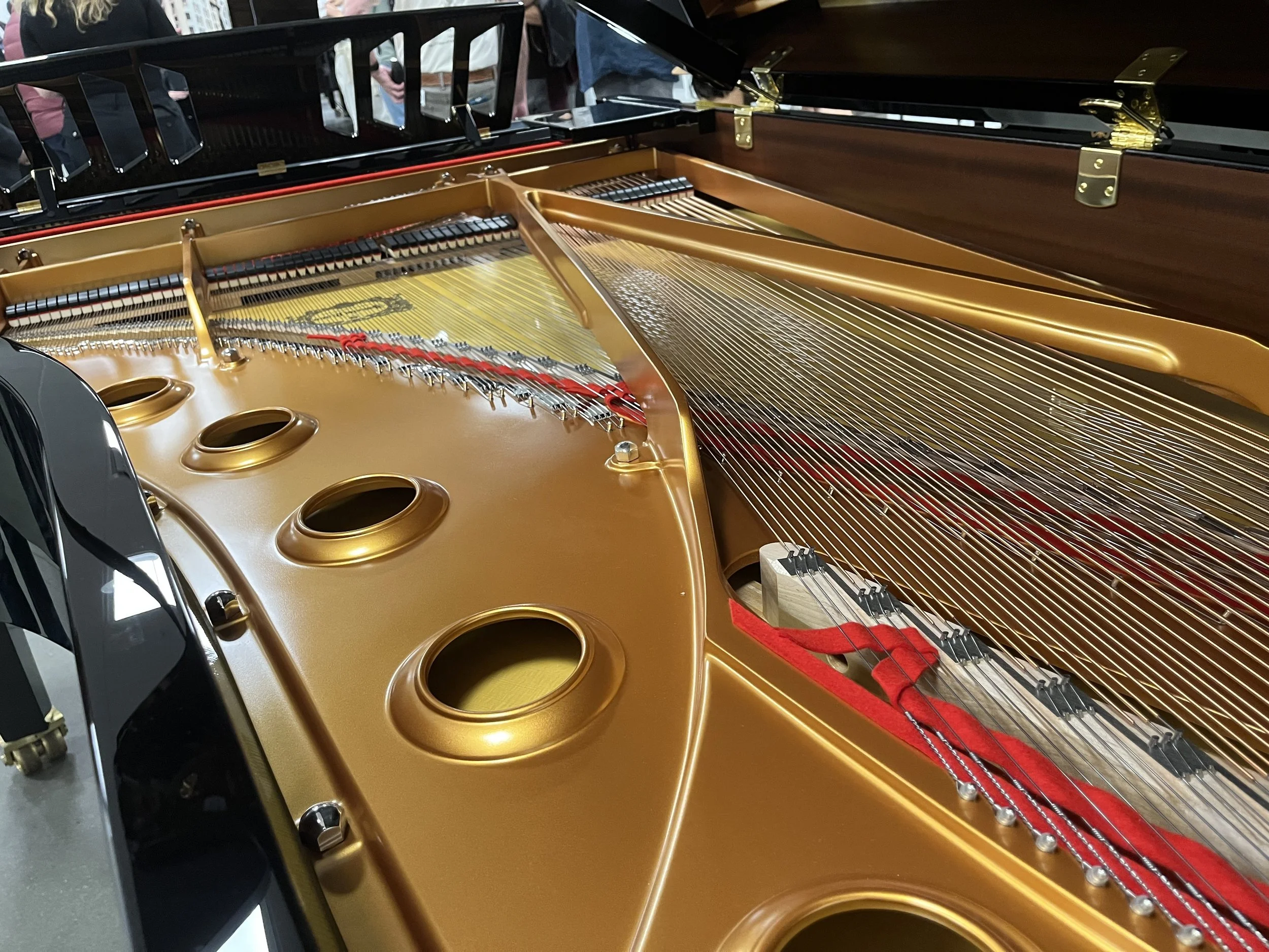 Close-up of the inside of a Yamaha concert grand piano showing the strings, sound holes, and wooden frame.