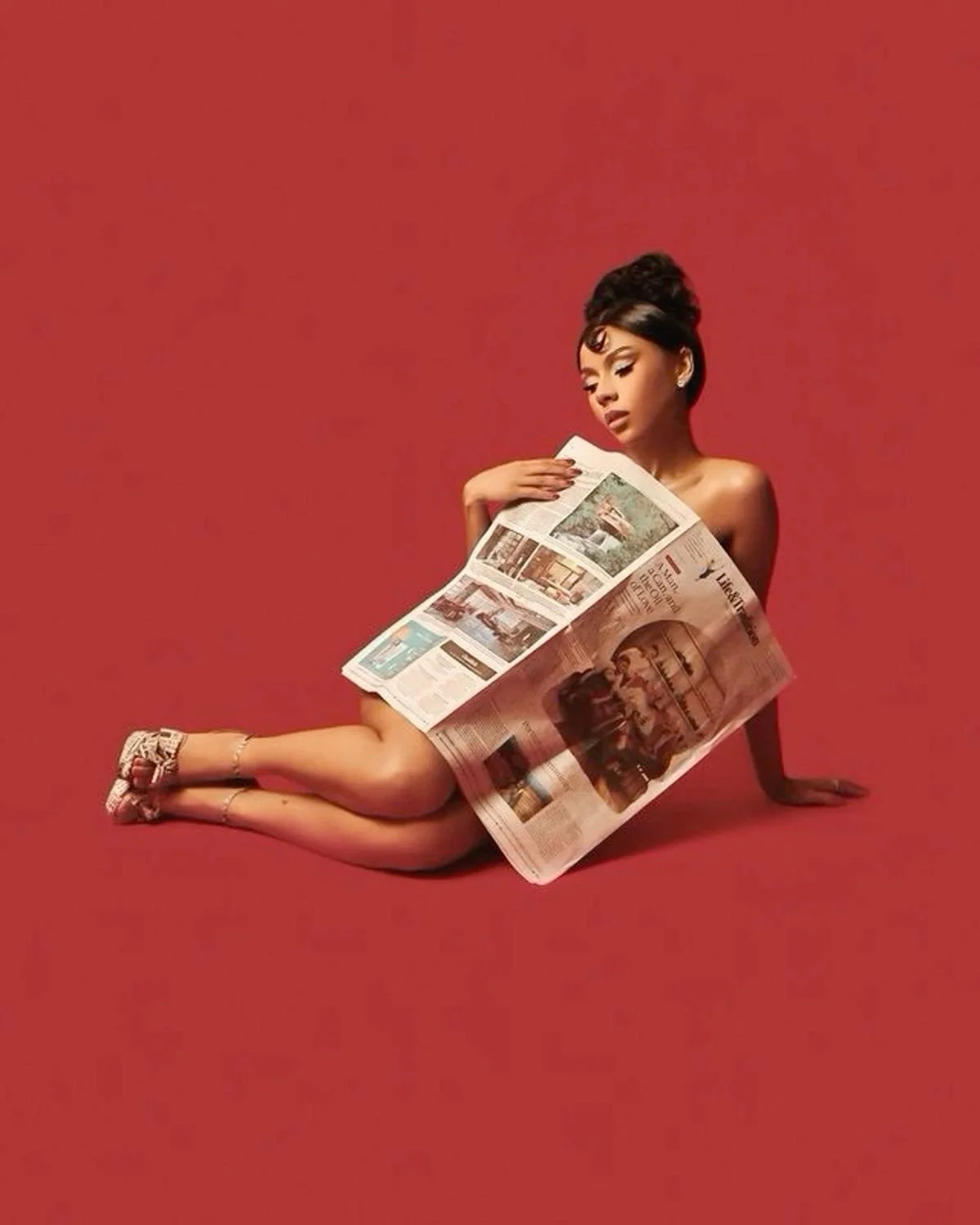 A woman with styled dark hair, wearing high heels, is sitting on the floor covered with a red background, reading a newspaper.