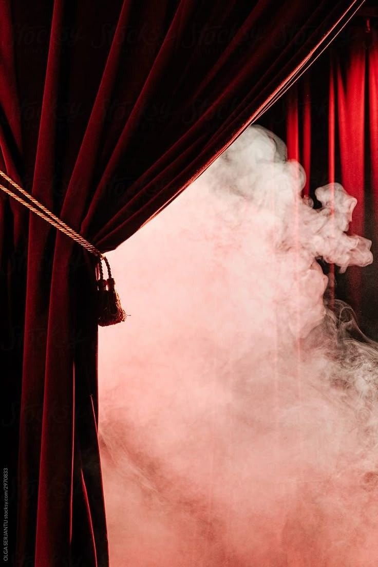 Stage with red velvet curtains opening to pink fog or smoke.