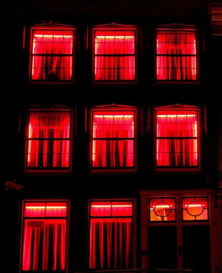 Building with nine windows illuminated by red neon lights, with curtains visible inside.