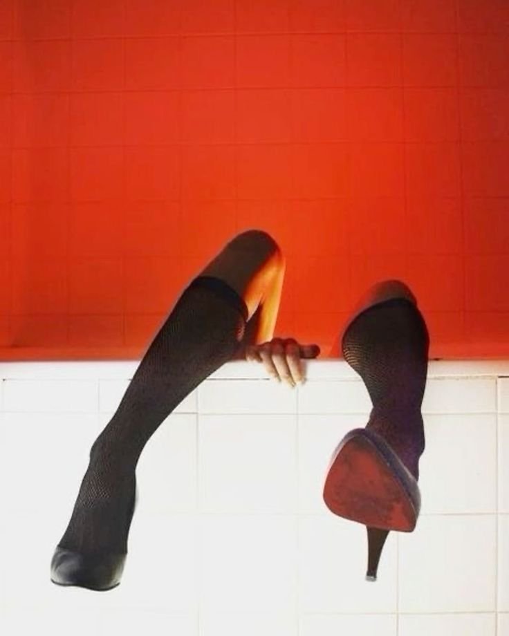 Footwear of a woman with one leg in a high heel shoe and the other leg missing, with only the shoe remaining.