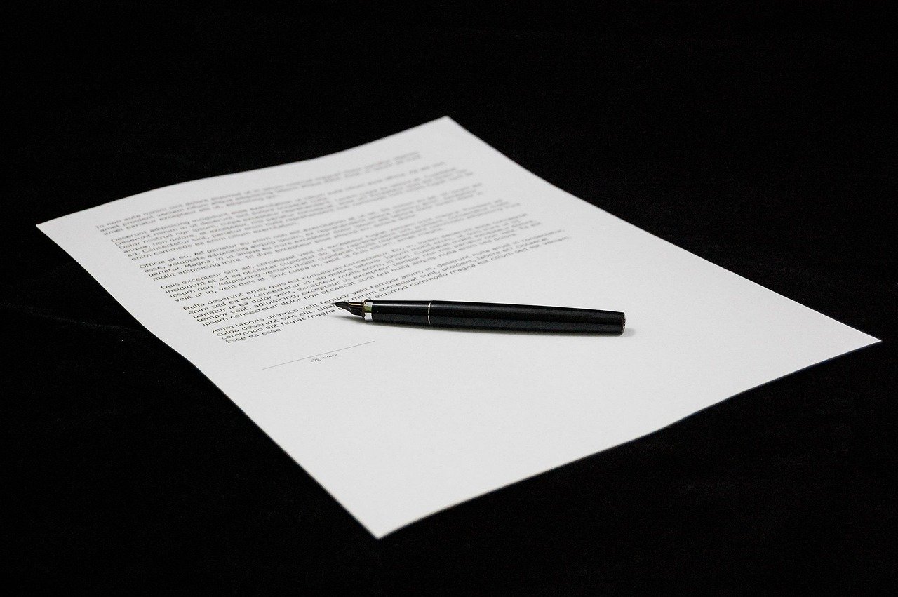 A black pen resting on a sheet of printed paper against a black background.