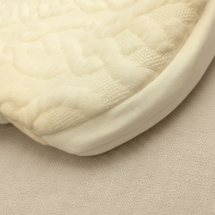 Bebetonスリーパーの生地アップ。表面は上品なケーブル編みキルト、裏地は肌に優しいオーガニックコットン。