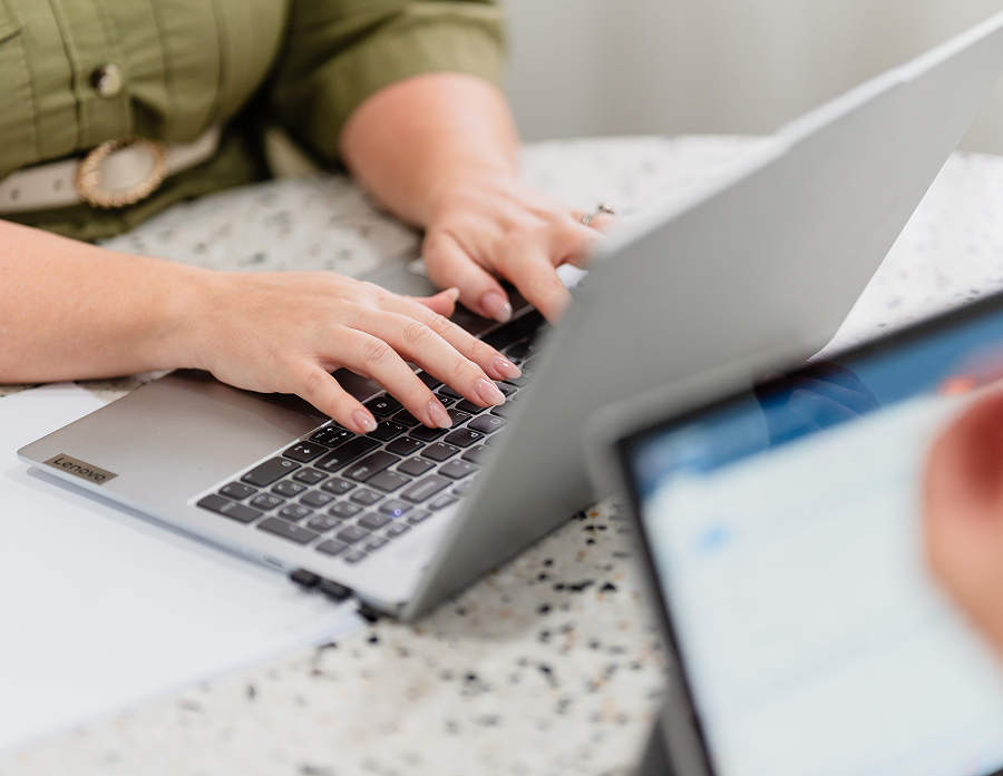 Person typing on a laptop keyboard at a desk.