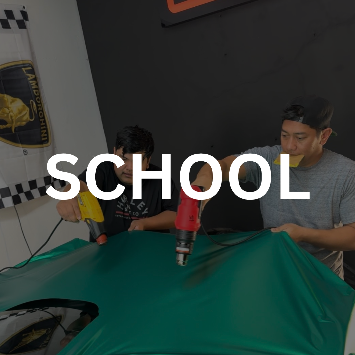 Two young men working on a project in a workshop with the word 'SCHOOL' overlaid in white text.