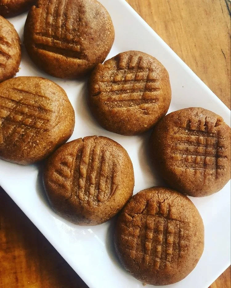 Six round, golden-brown cookies with grid patterns on top, arranged on a white rectangular plate.