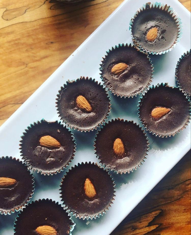 Chocolate cupcakes with an almond on top, arranged on a white rectangular tray.