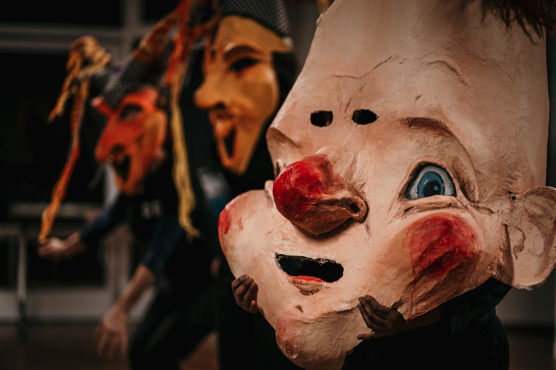 Performers holding oversized theatrical masks during Perth French Theatre’s production of Pinocchio.