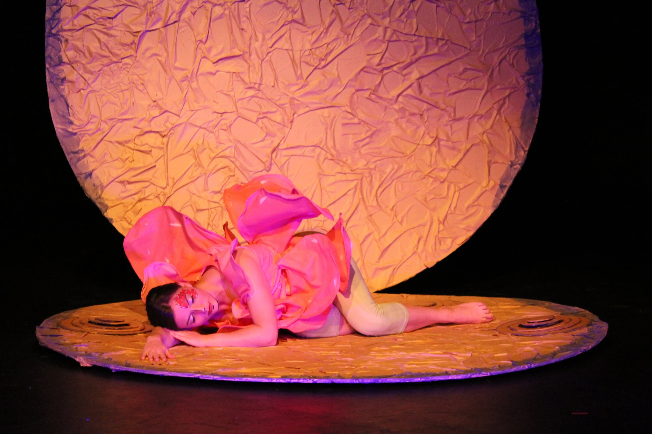 Performer beside a large illuminated sphere during a Perth French Theatre production.