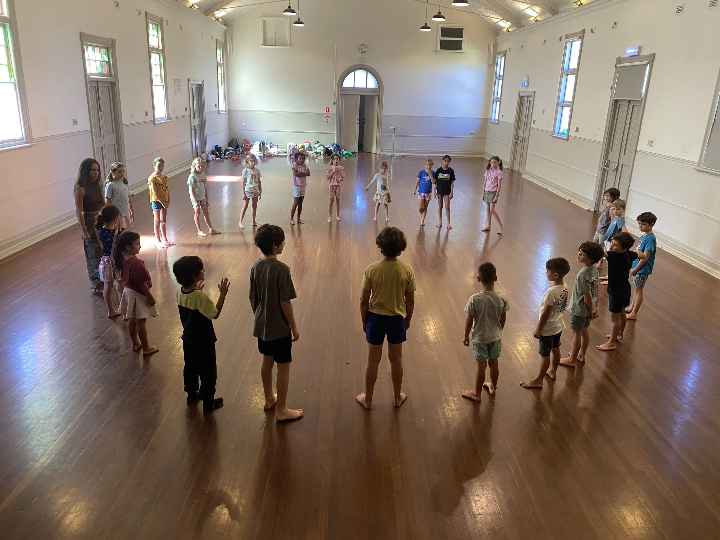 Children standing in a circle during a French Holiday Program theatre and movement activity in Perth.