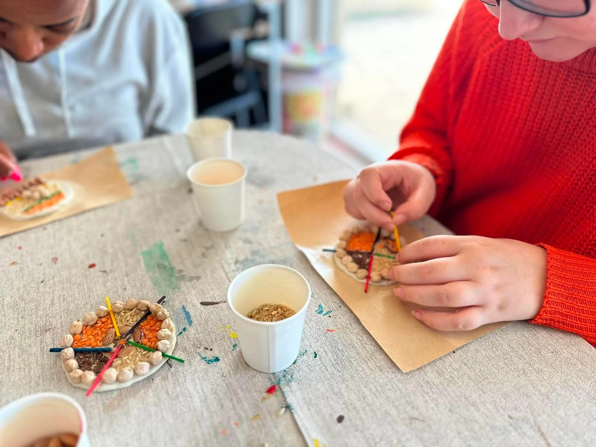 Mess Hall participants decorating clay pieces during a creative workshop.