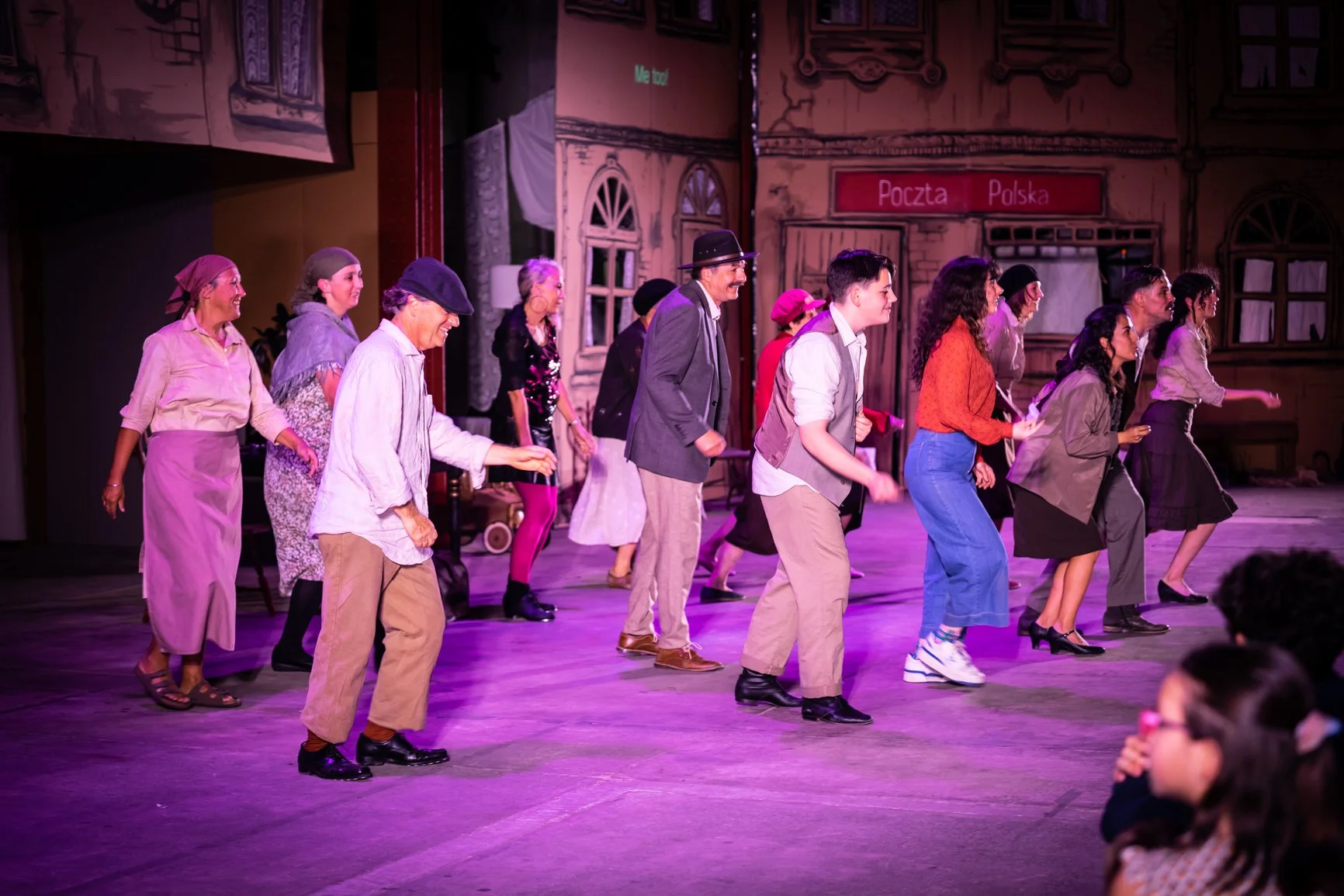 Perth French Theatre ensemble performing a lively scene from Les Crapauds Fous on a Polish street set.