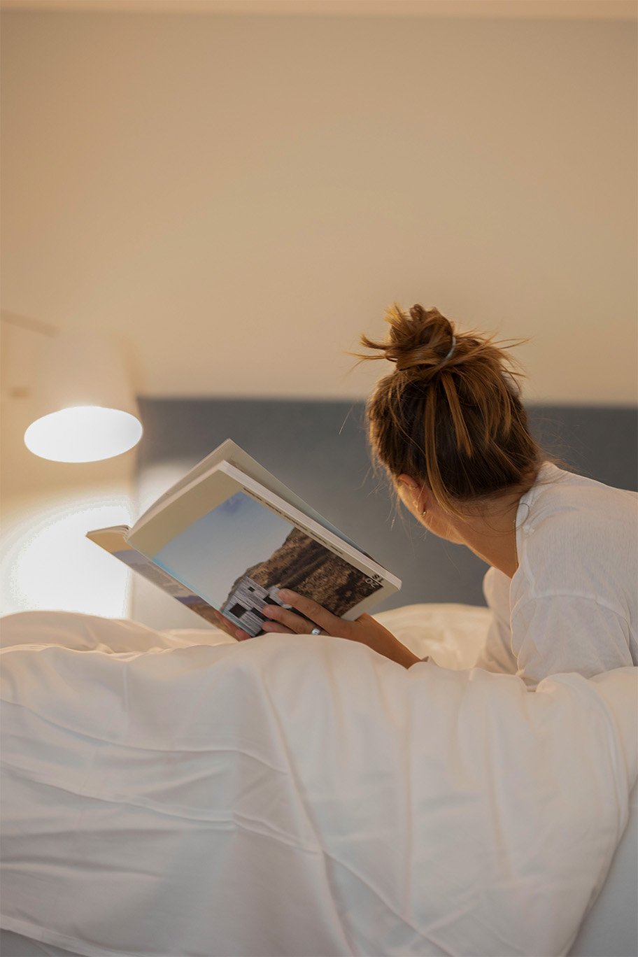 Frau liest im Bett in der Ferienwohnung Ferienbox – Fokus auf Entspannung und modernes Design