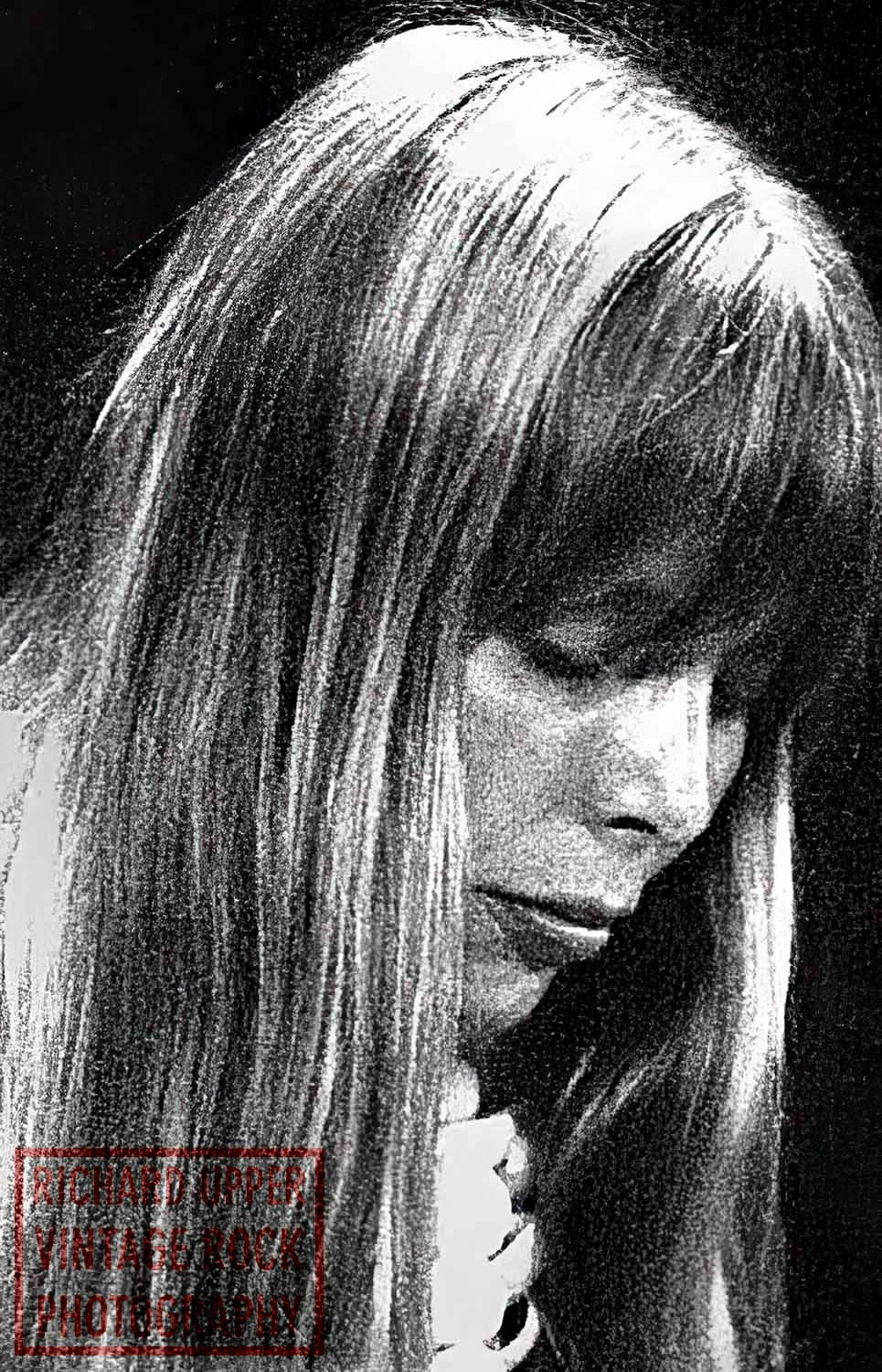 A black and white vintage-style photograph of a woman with long hair, looking down thoughtfully.
