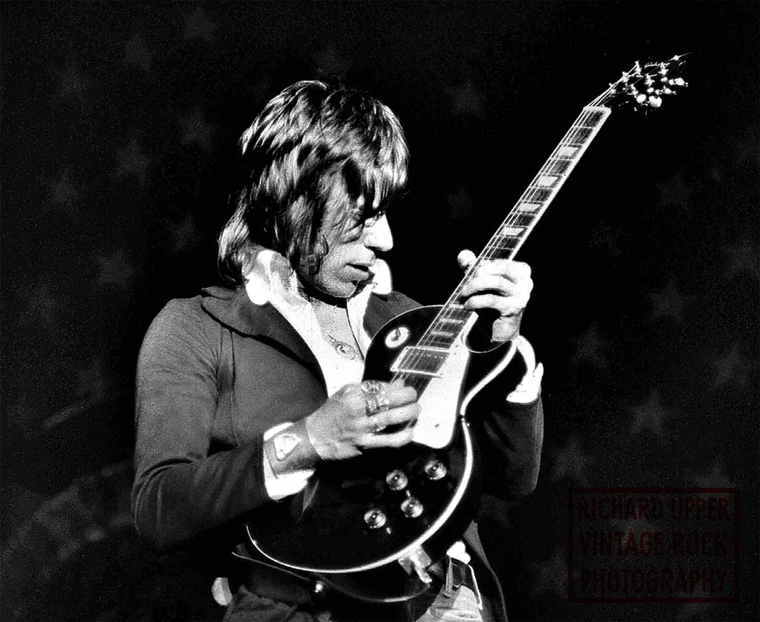 Black and white photo of a person with long hair playing an electric guitar.