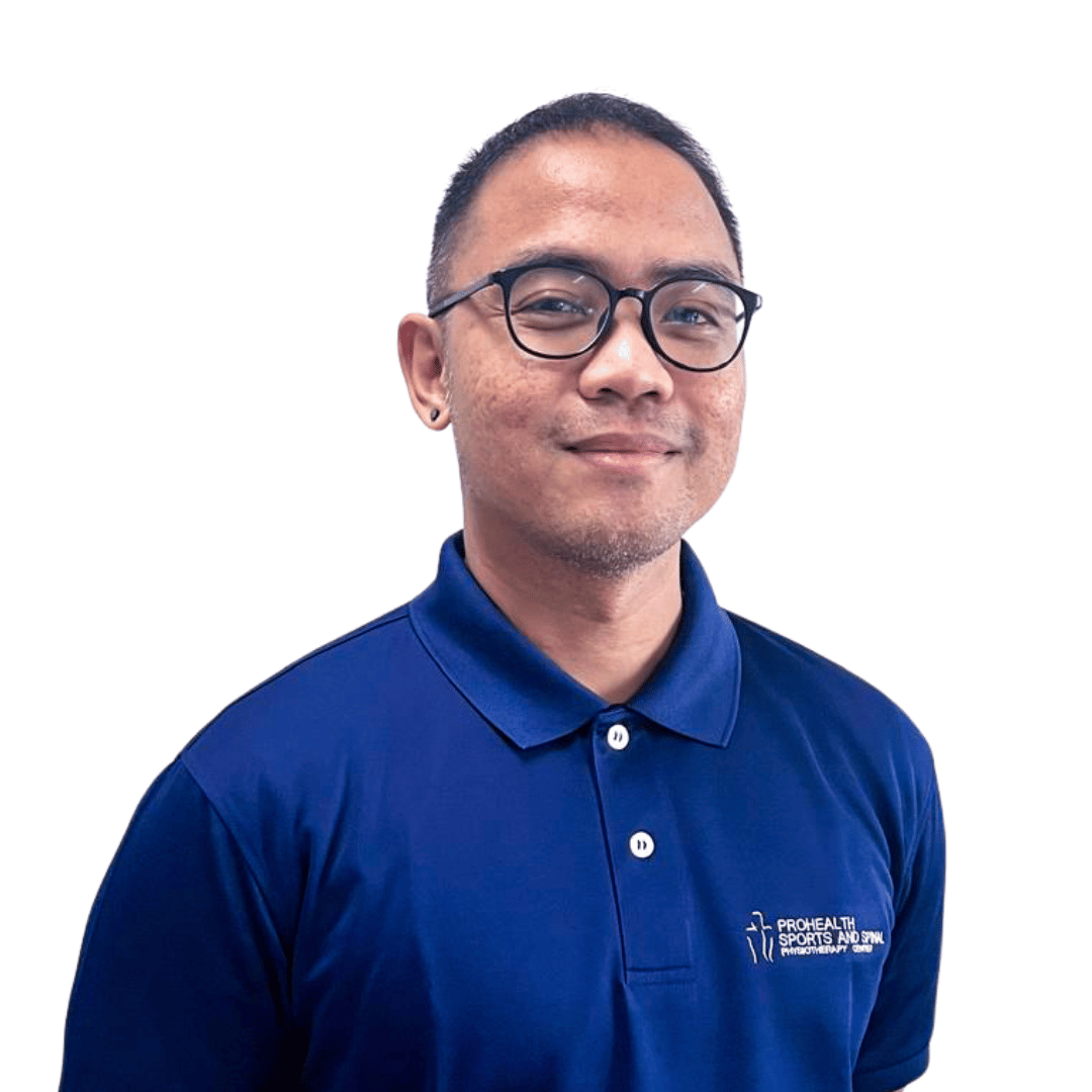 A man with short dark hair, glasses, and a small earring, wearing a navy blue polo shirt with a logo that reads 'Prohealth Sports and Spine Physiotherapy Clinic', standing against a plain white background.