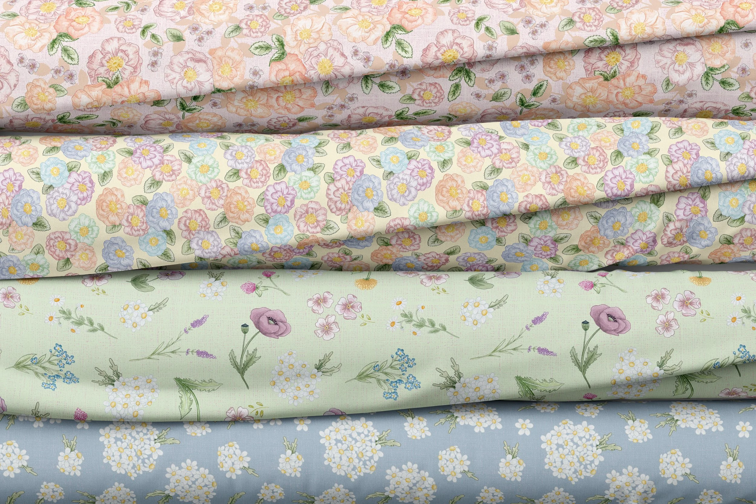 Four rolls of floral-patterned fabric stacked on top of each other, featuring pastel-colored flowers on light backgrounds.