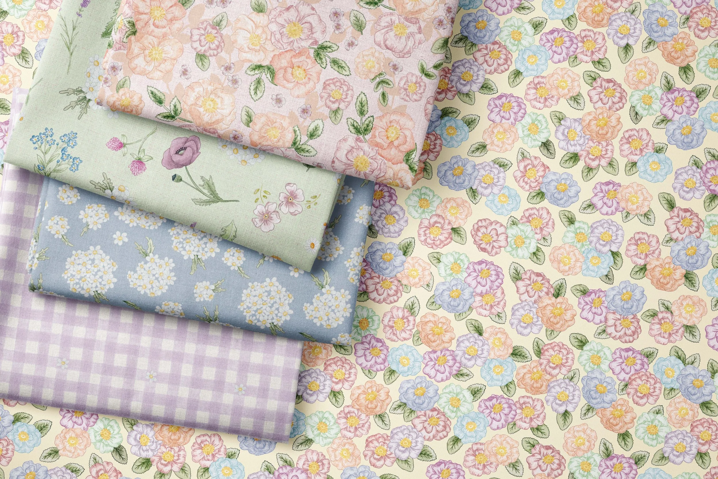 Stack of four folded floral patterned fabrics in pastel colors, laid on a floral patterned fabric background.