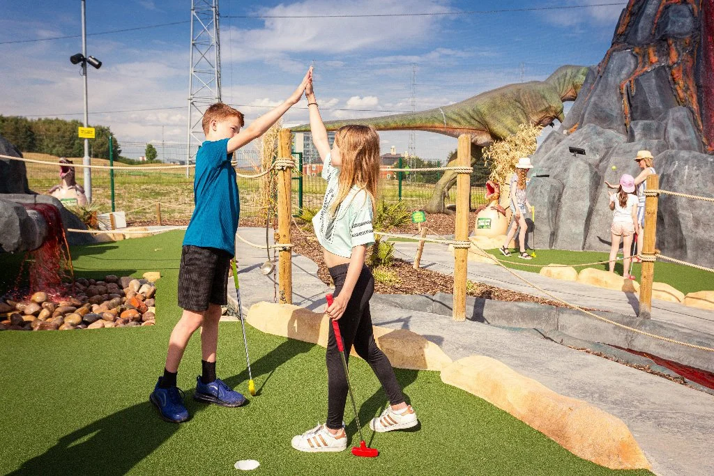 Boy and girl high fiving on adventure golf course