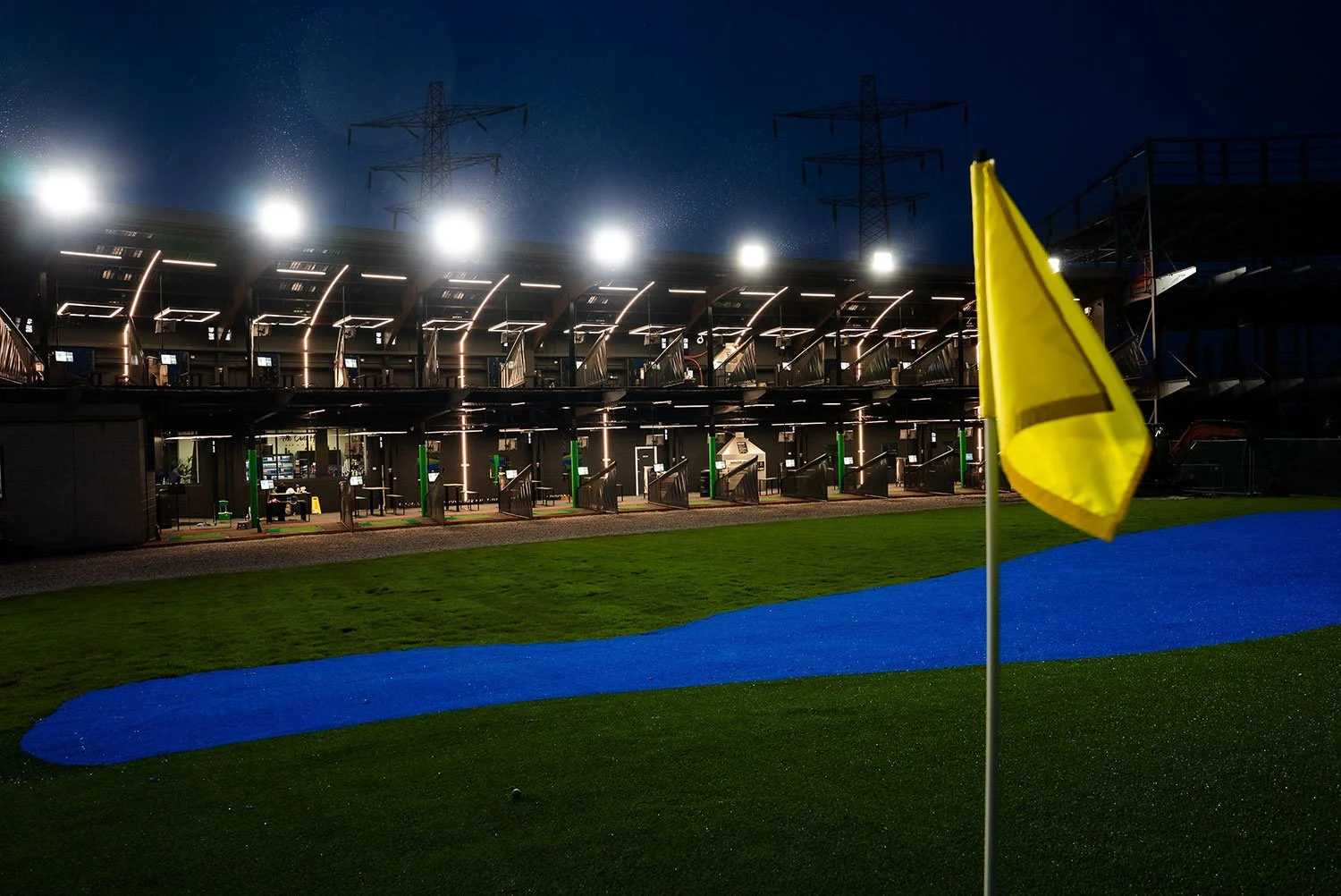 View of driving range bays and yellow flag at night