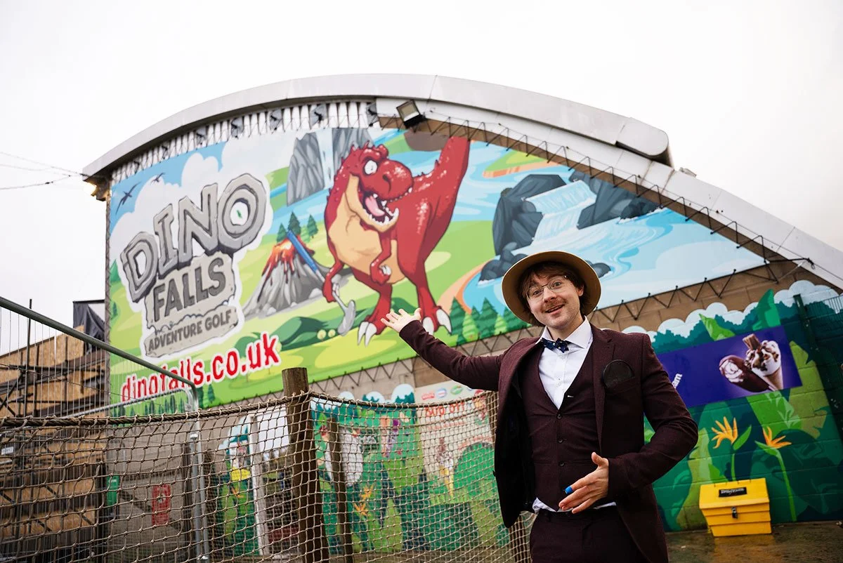 Man in brown suit pointing at sign