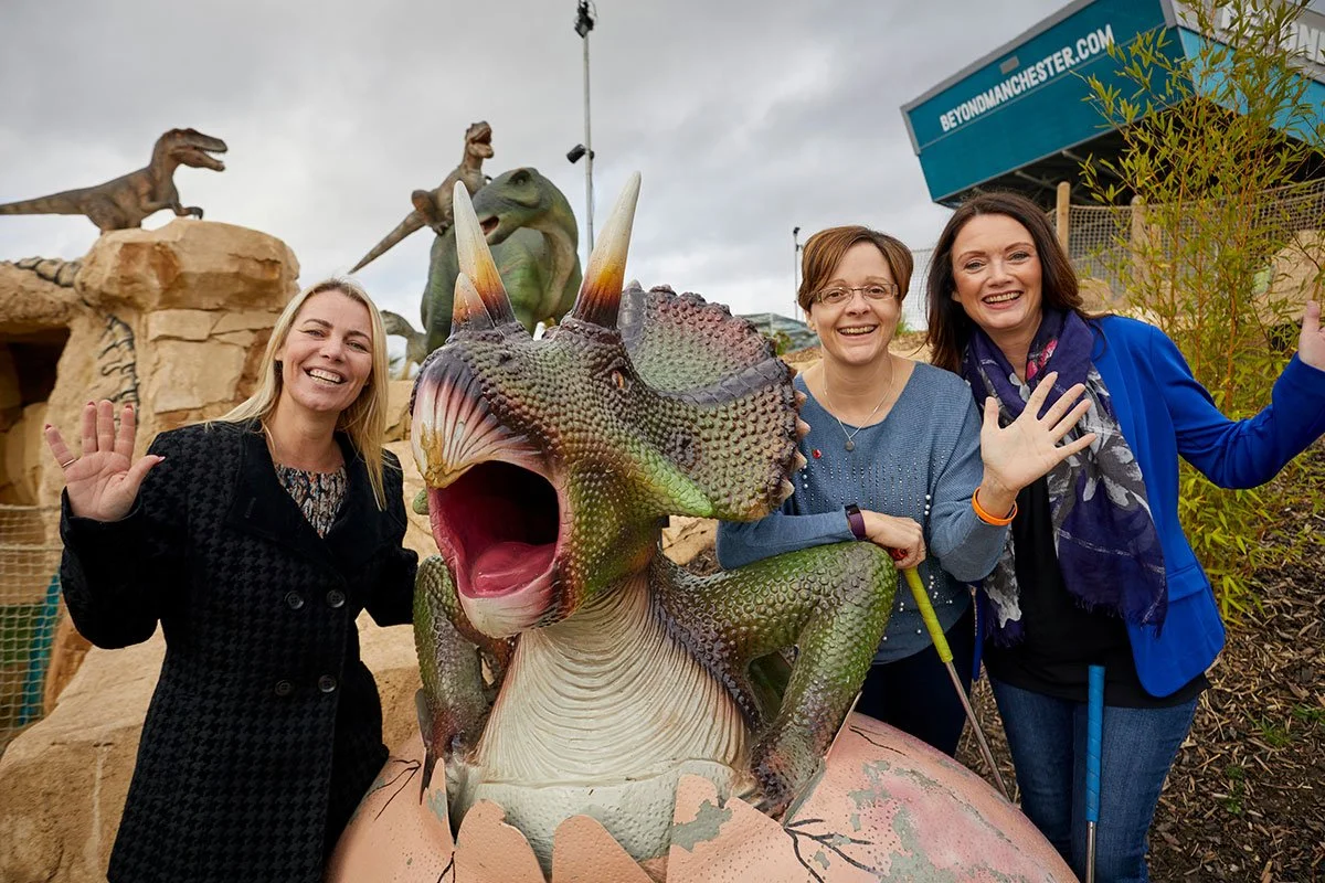 Women smiling with a dinosaur model