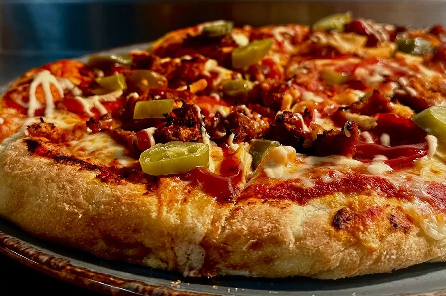 Close up of sourdough crust meat and pepper pizza