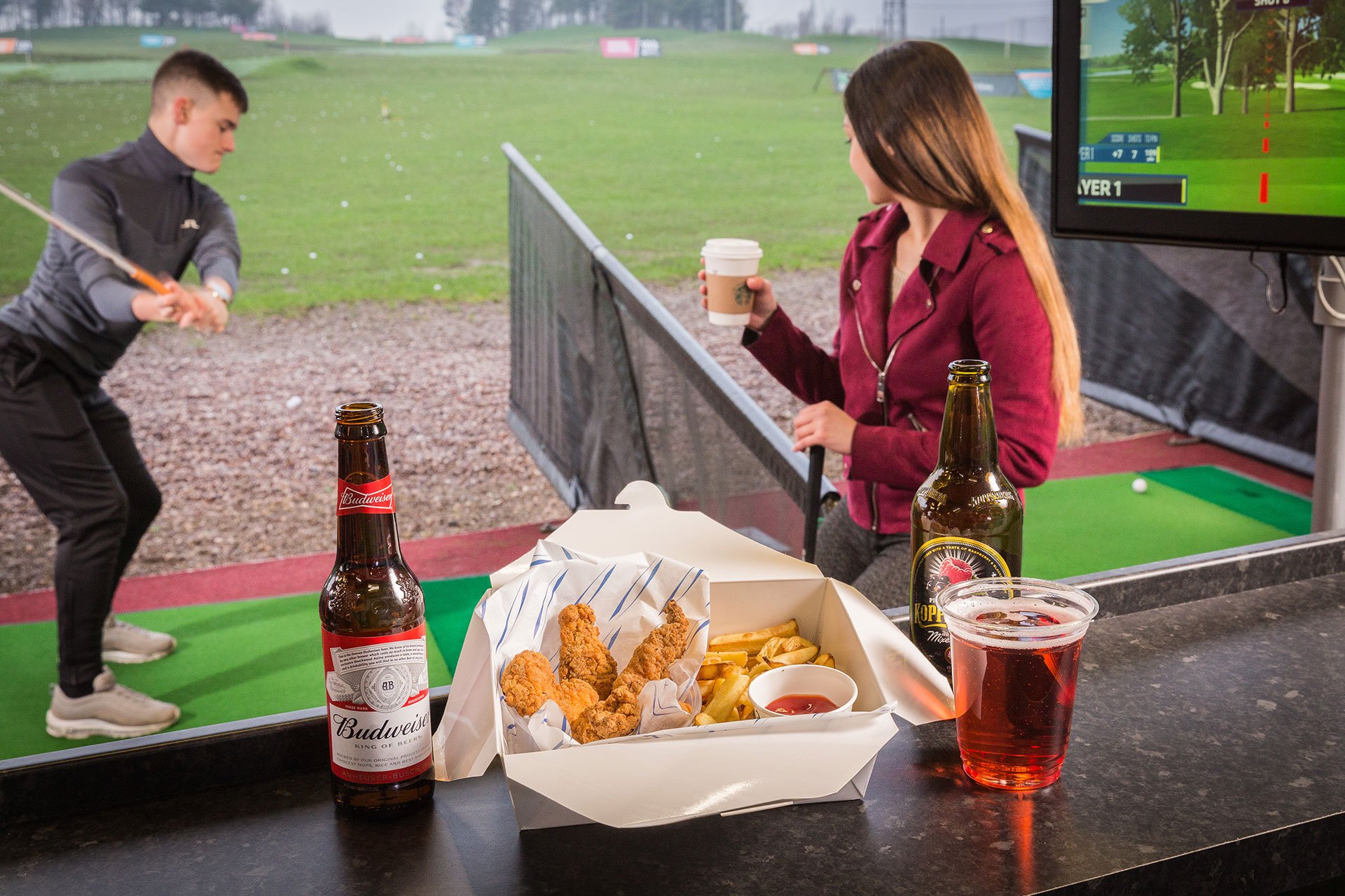 Girl with a drink, and food on the side of a golf bay