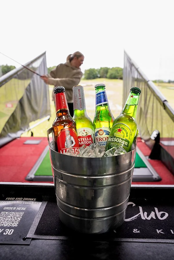 Person playing golf in background of bucket of beer