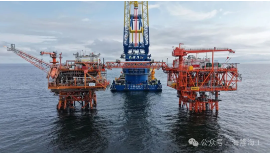 Offshore oil drilling platform in the ocean with a large crane in the center and two smaller platforms on either side.