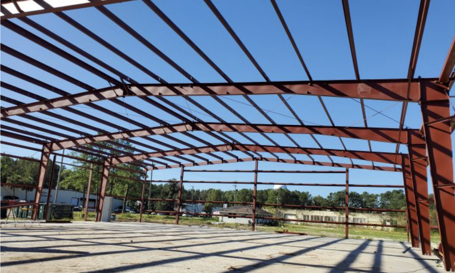 Steel framework of an empty outdoor pavilion or shelter with a blue sky background.