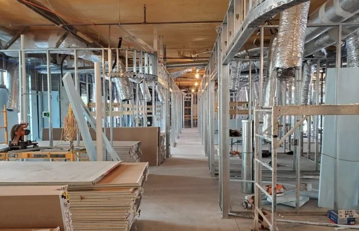 Construction site with exposed metal framing, ductwork, and building materials.