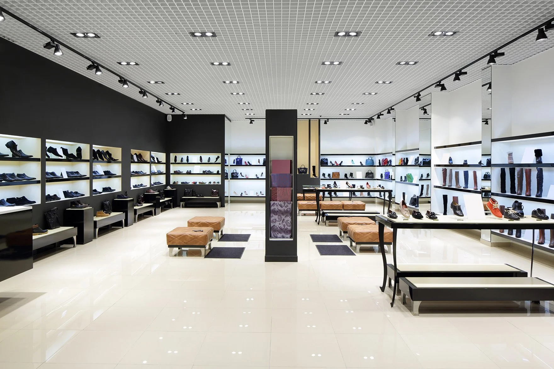 A shoe store interior with shelves of various footwear, benches, and display tables.