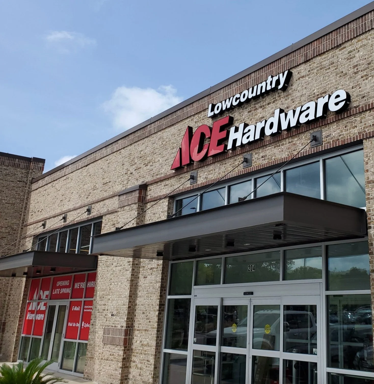 Front view of a Lowcountry ACE Hardware store, with brick exterior, glass doors, and a sign displaying the store's name.