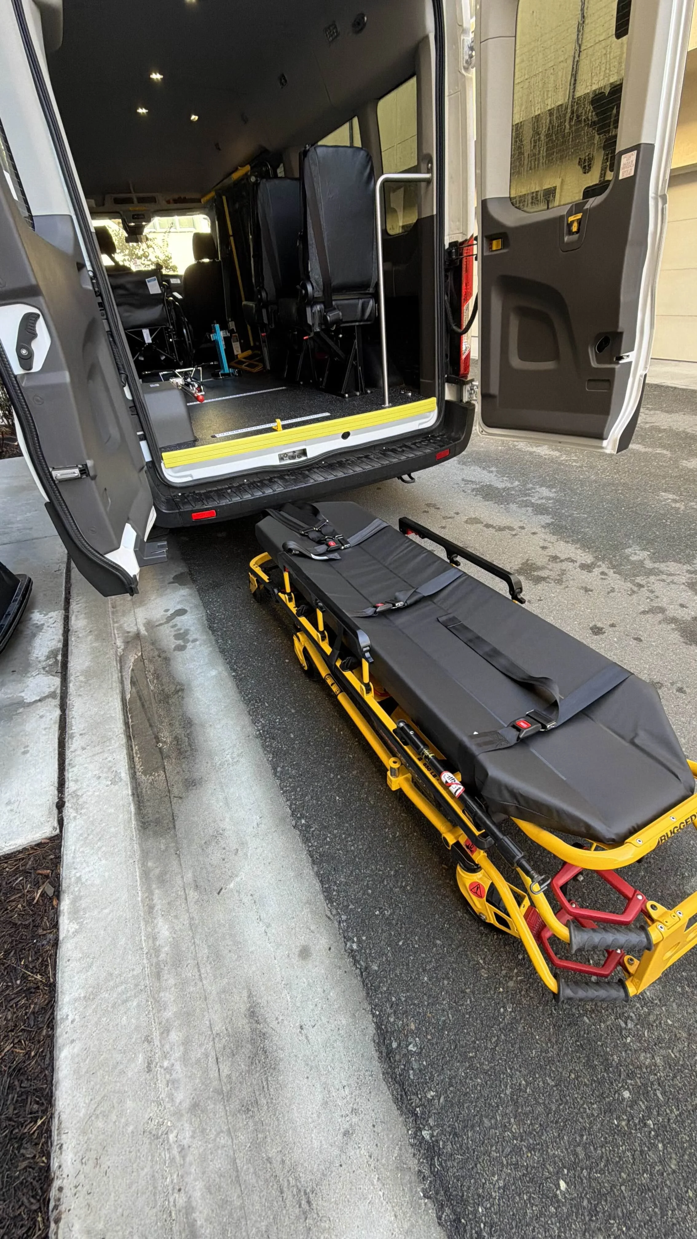 Emergency medical vehicle with a stretcher outside its open rear door, ready for patient transport.
