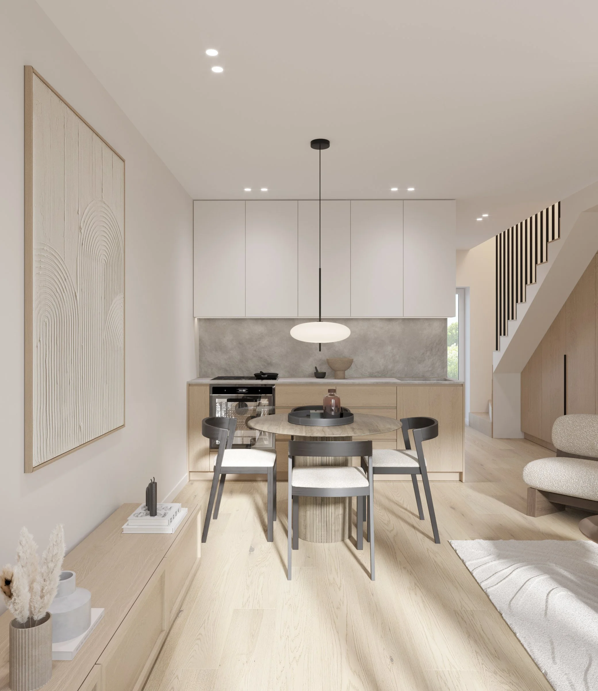 Modern open-plan kitchen and dining area with light wood flooring, white and light wood cabinets, round dining table with four chairs, black pendulum light, beige sofa, and staircase with black railing.