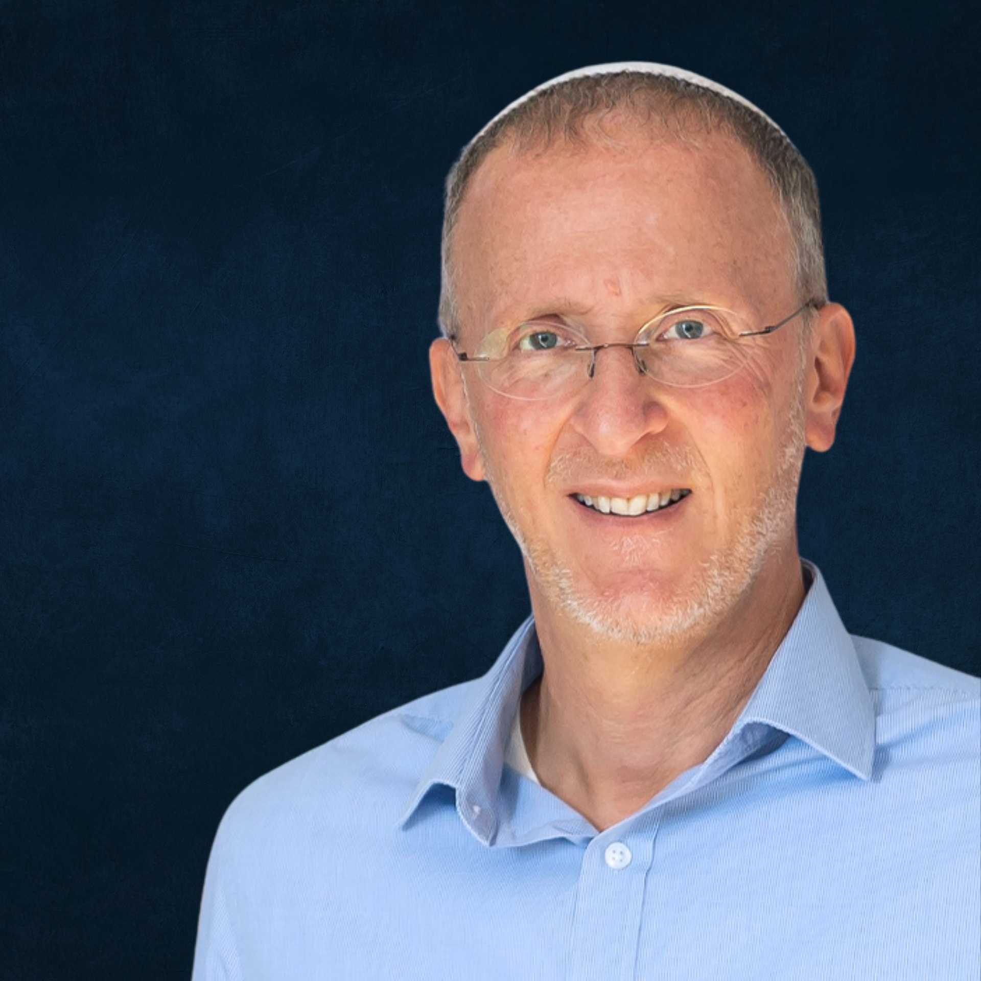 Headshot of a smiling middle-aged man with glasses, light blue dress shirt, and a dark background.