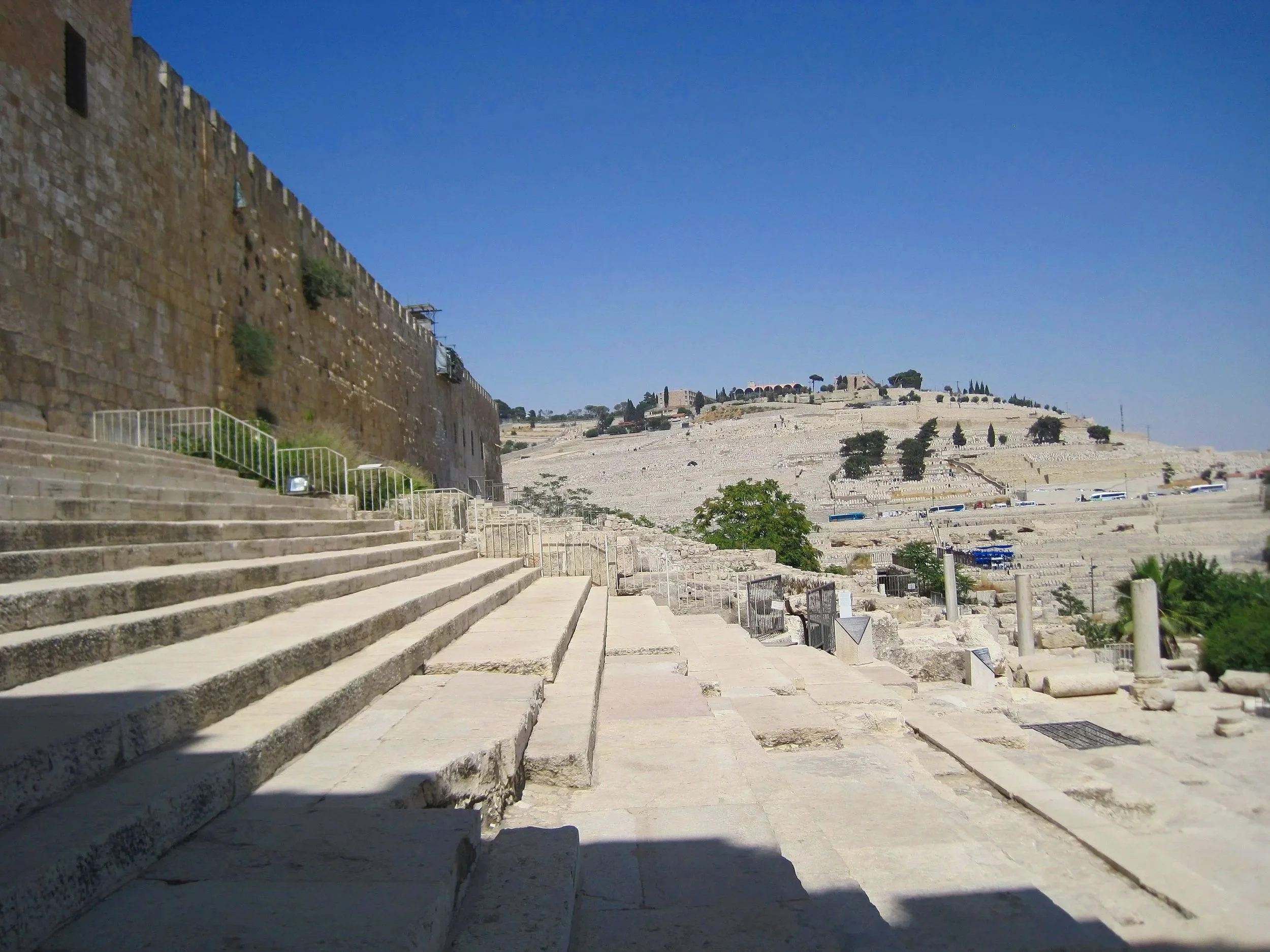 Ancient stone steps Leading up to a historical site, with a hillside in the background, clear blue sky, and sparse vegetation.