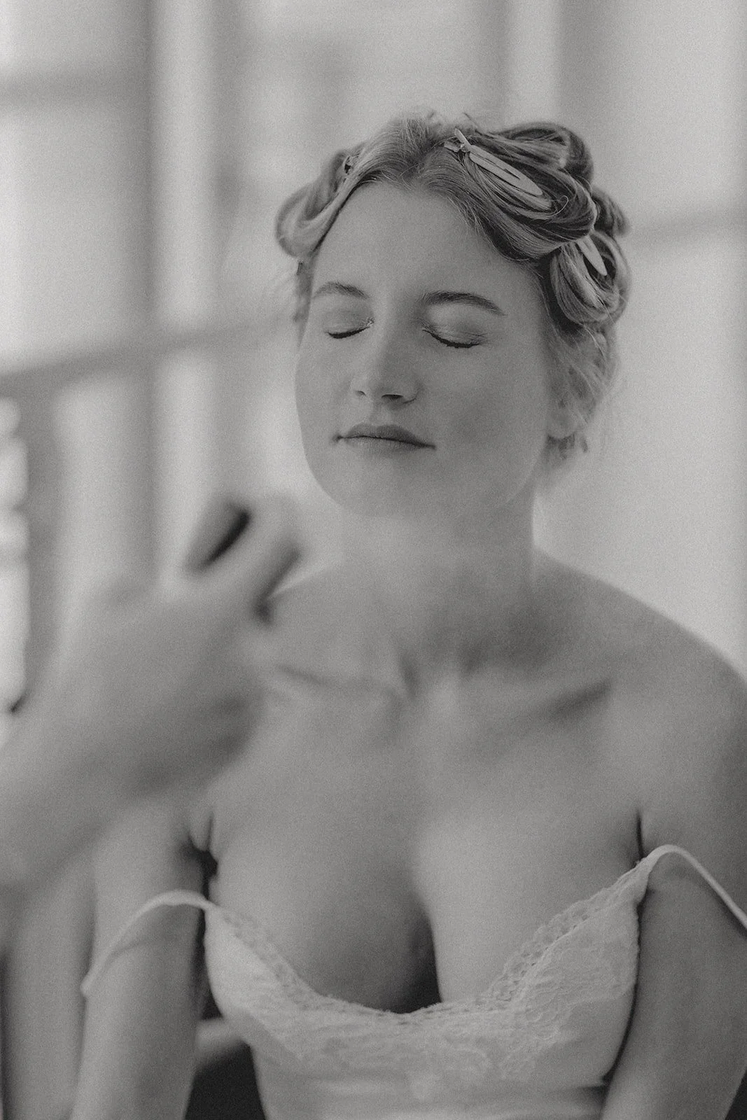 Eine lächelnde Frau mit welligem Haar, die vor einem Spiegel steht und sich ansieht.