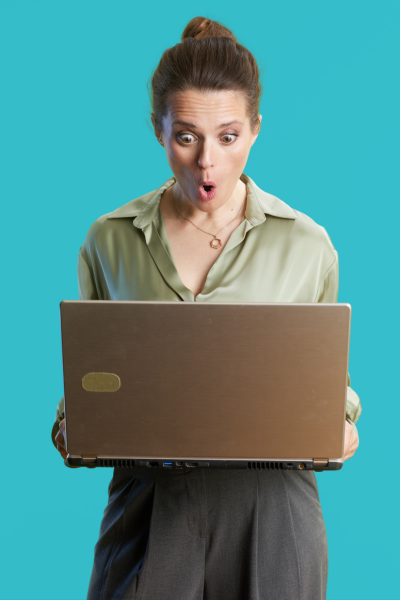 Une femme regarde un ordinateur portable avec une expression de surprise.