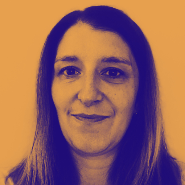 Portrait d'une femme avec long cheveux, souriant devant un mur beige.