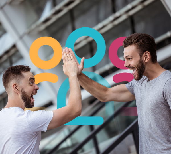 Deux hommes se félicitent avec un high five dans un lieu moderne avec des décorations colorées au mur.