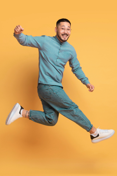 Homme souriant sautant avec un fond orange