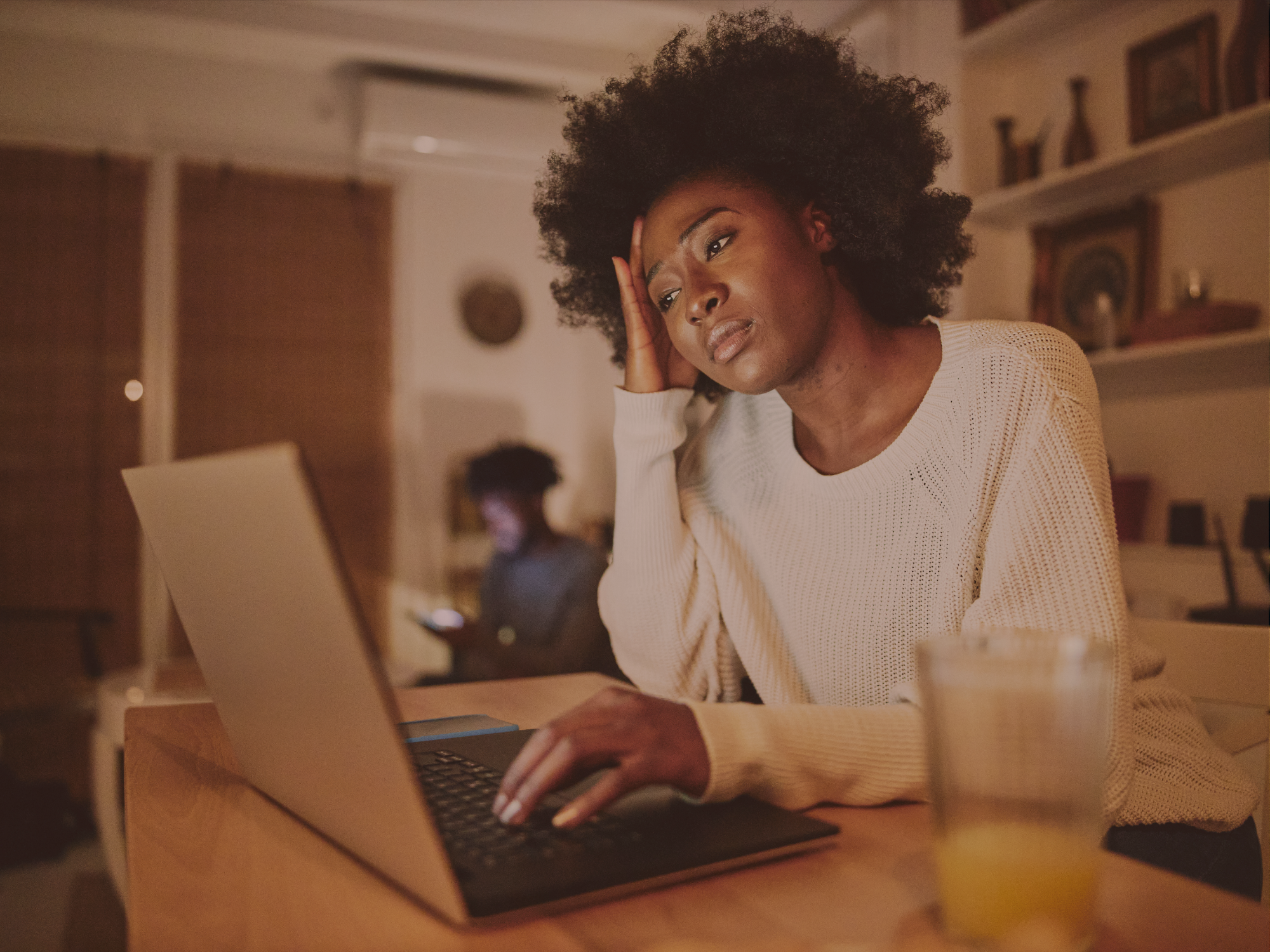 Black woman sitting next to laptop, looking stressed