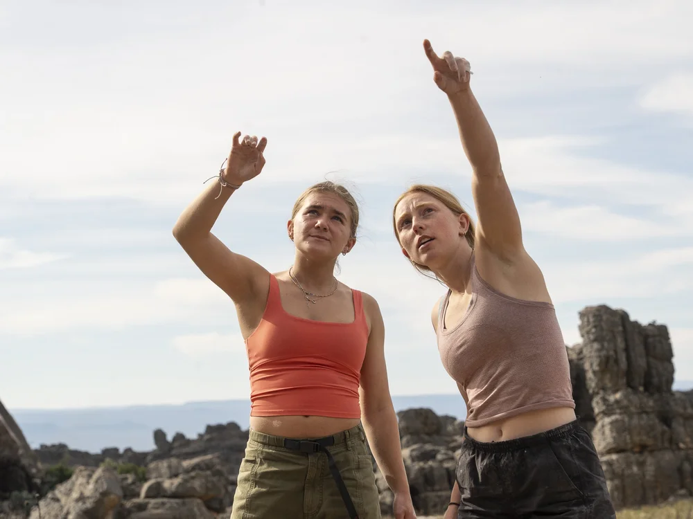 Two athletes pointing out a line on the boulder above them