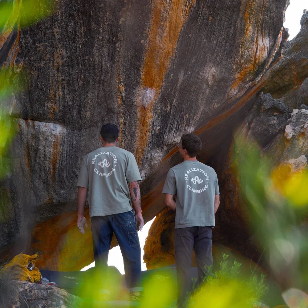 Two coaches studying a tall sandstone boulder