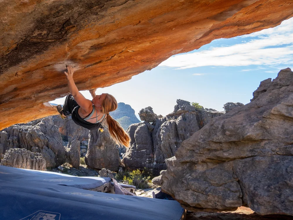 A teen climber bouldering under a huge orange sandstone roof in Rocklands