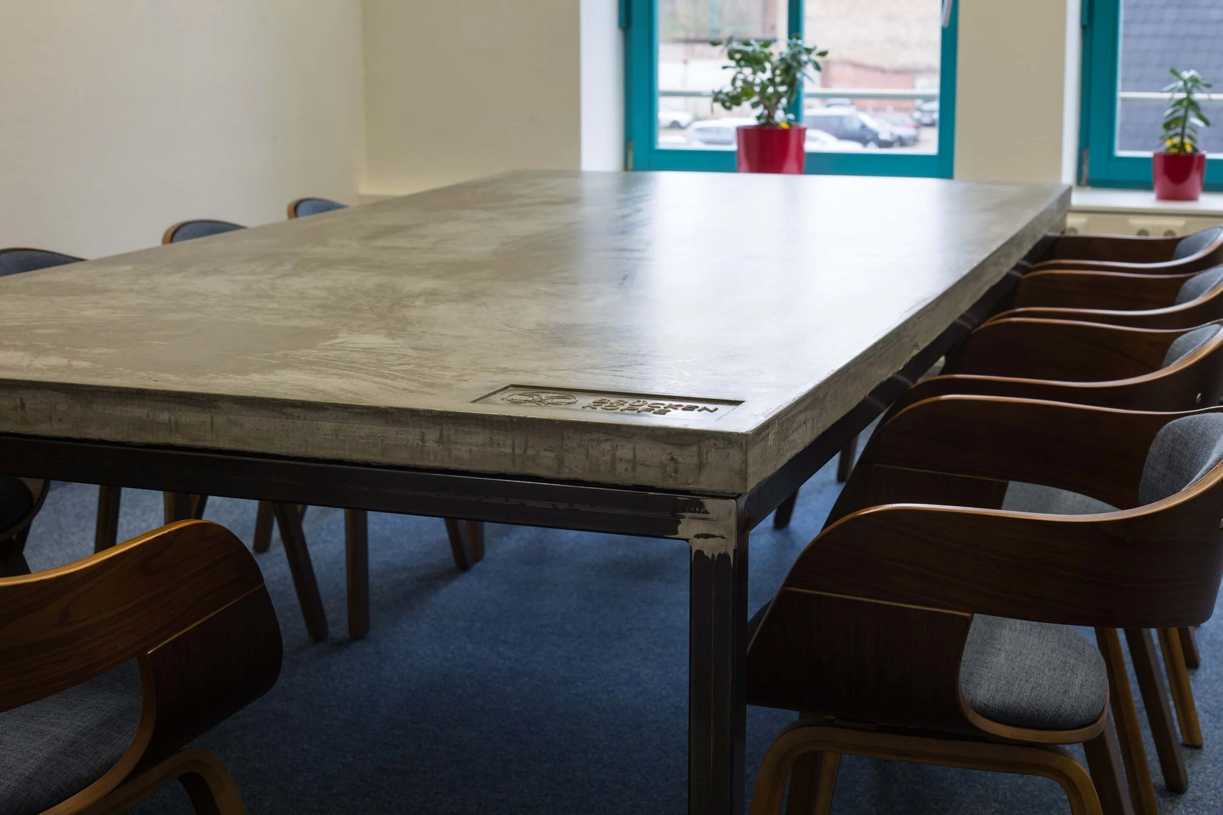 Großer Konferenztisch aus Beton mit Logo Gravur Brückenköpfe.
