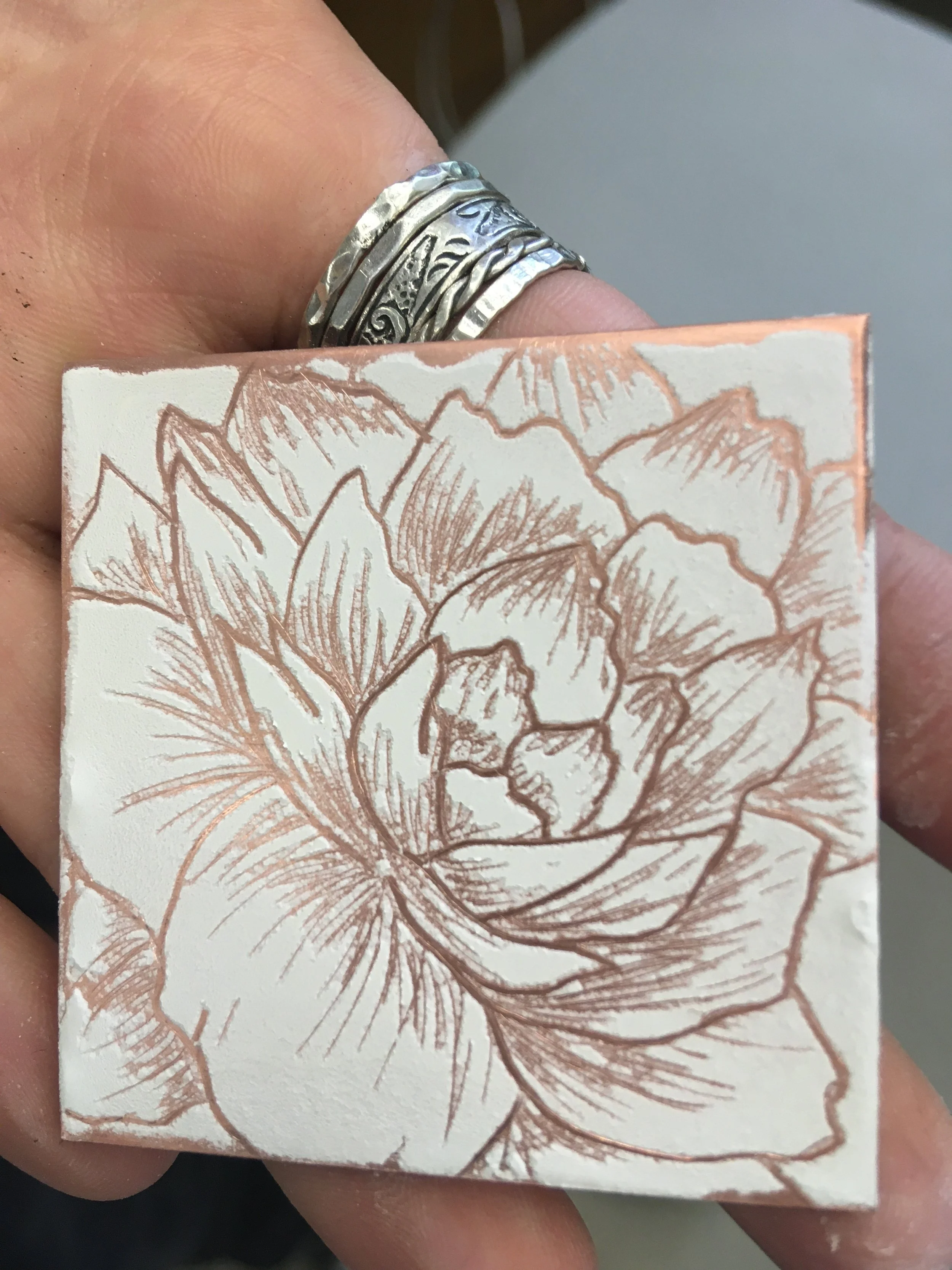 Young artist demonstrating the sgrafitto technique of drawing into the enamel before the firing.